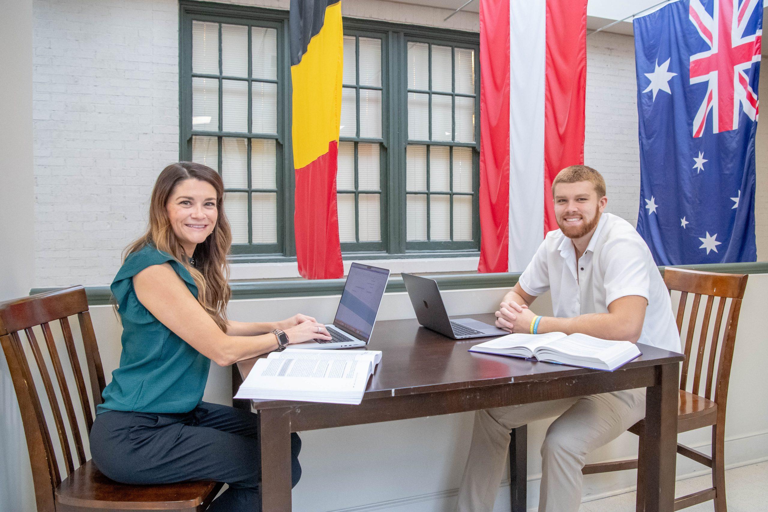 Two students working on assignment together in the College of Business and Aviation, both with a laptops and textbooks.